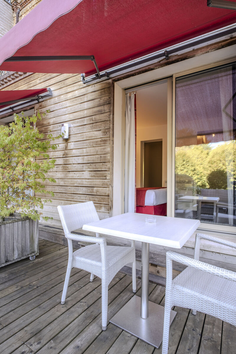 Terrasse en bois sous les stores rouges du Manoir de Sauvegrain