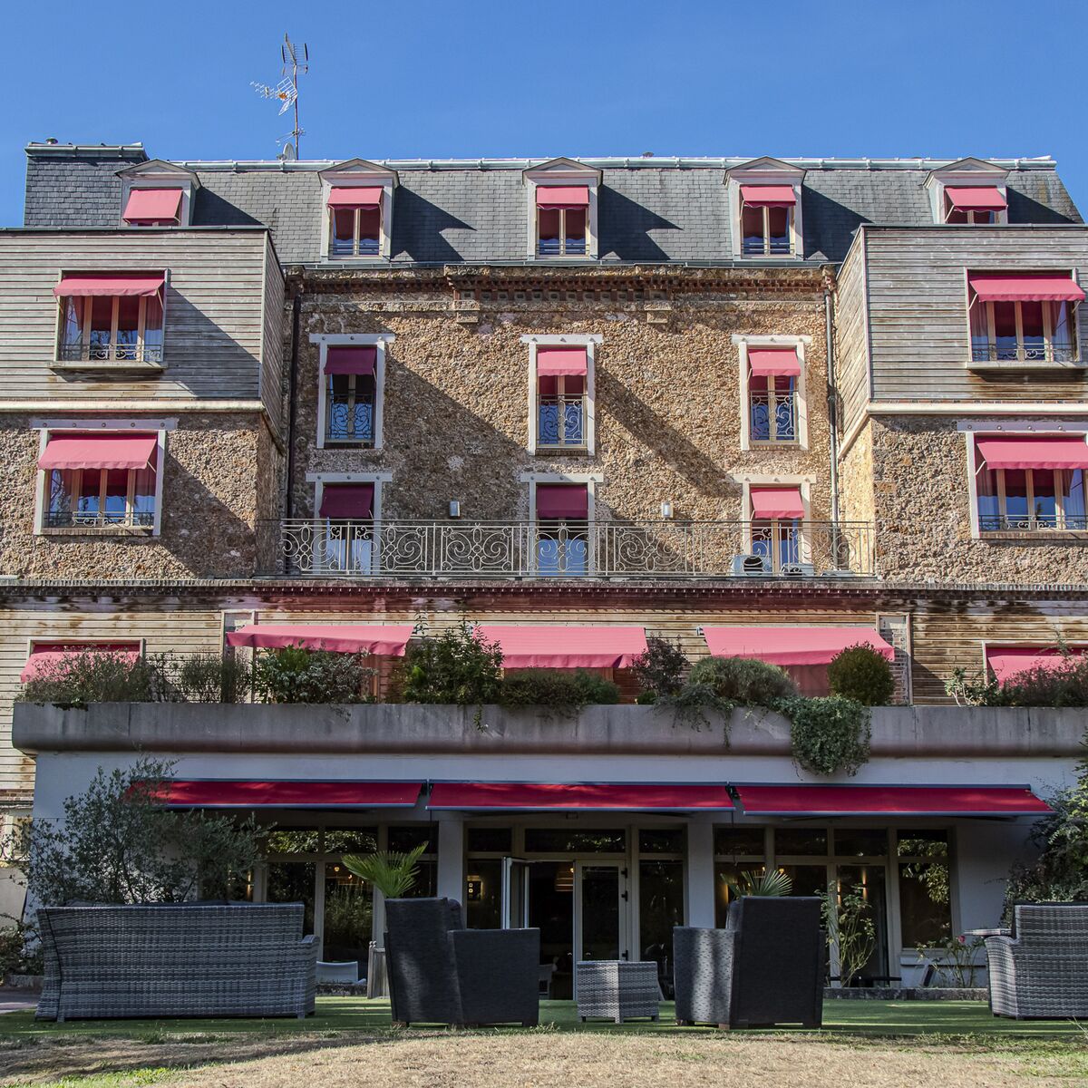 Façade et terrasse du Manoir de Sauvegrain sous les stores rouges