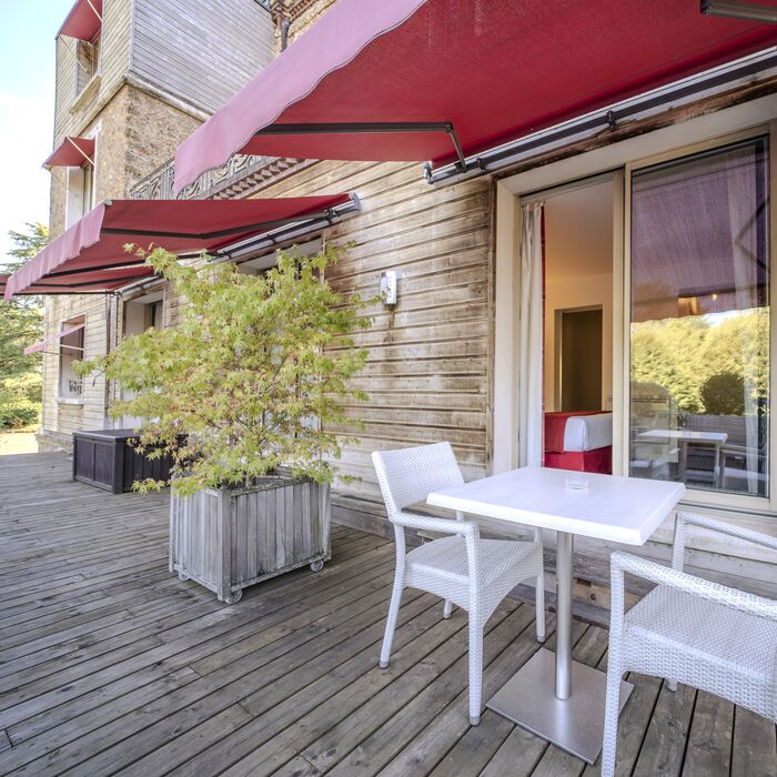 Terrasse en bois sous les stores rouges du Manoir de Sauvegrain