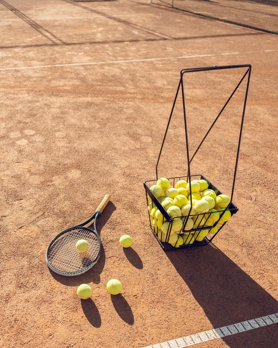 Raquette et balles sur un court de tennis, prêtées par le Manoir de Sauvegrain